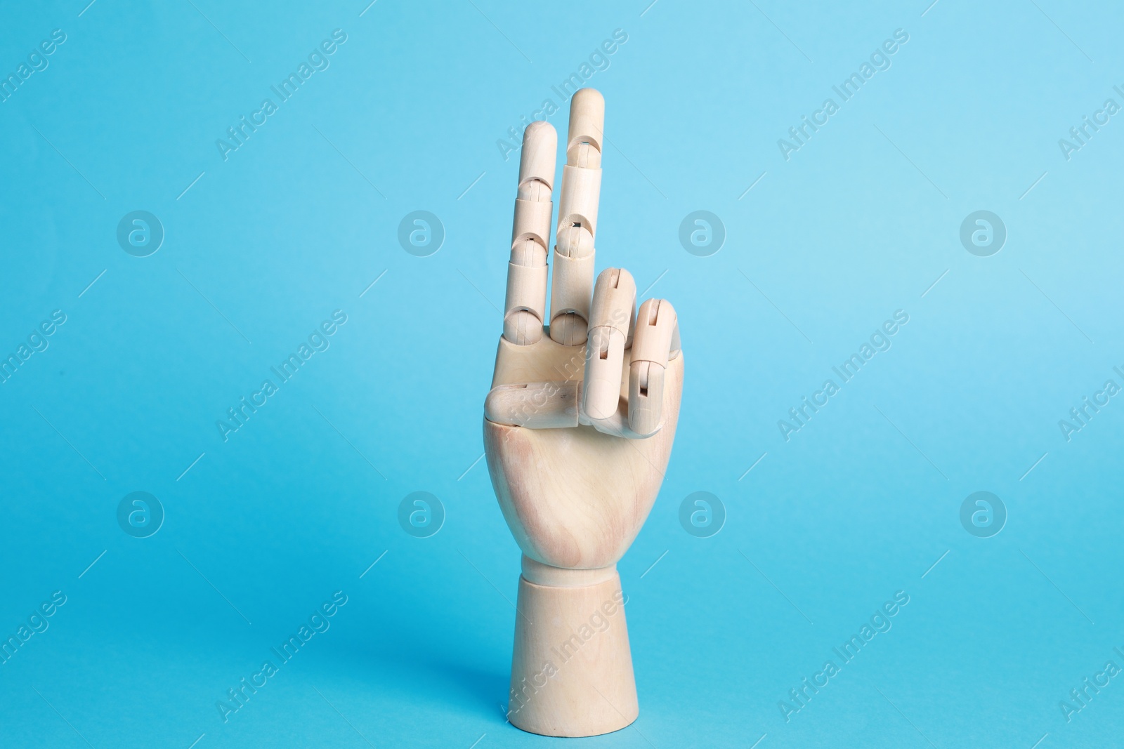 Photo of Wooden hand model on light blue background. Mannequin part