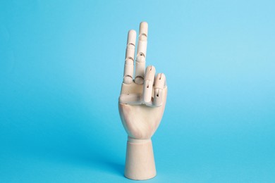 Photo of Wooden hand model on light blue background. Mannequin part