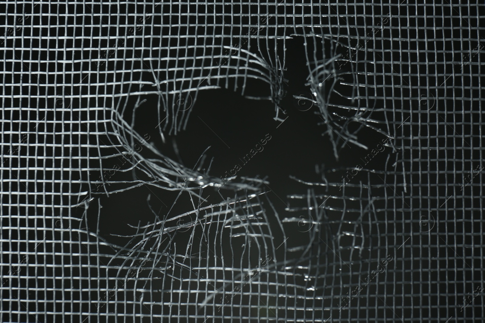 Photo of Torn window screen against black background, closeup