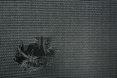 Photo of Torn window screen against black background, closeup