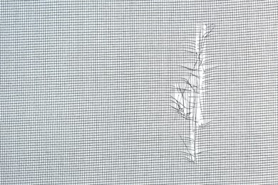 Photo of Torn window screen against white background, closeup