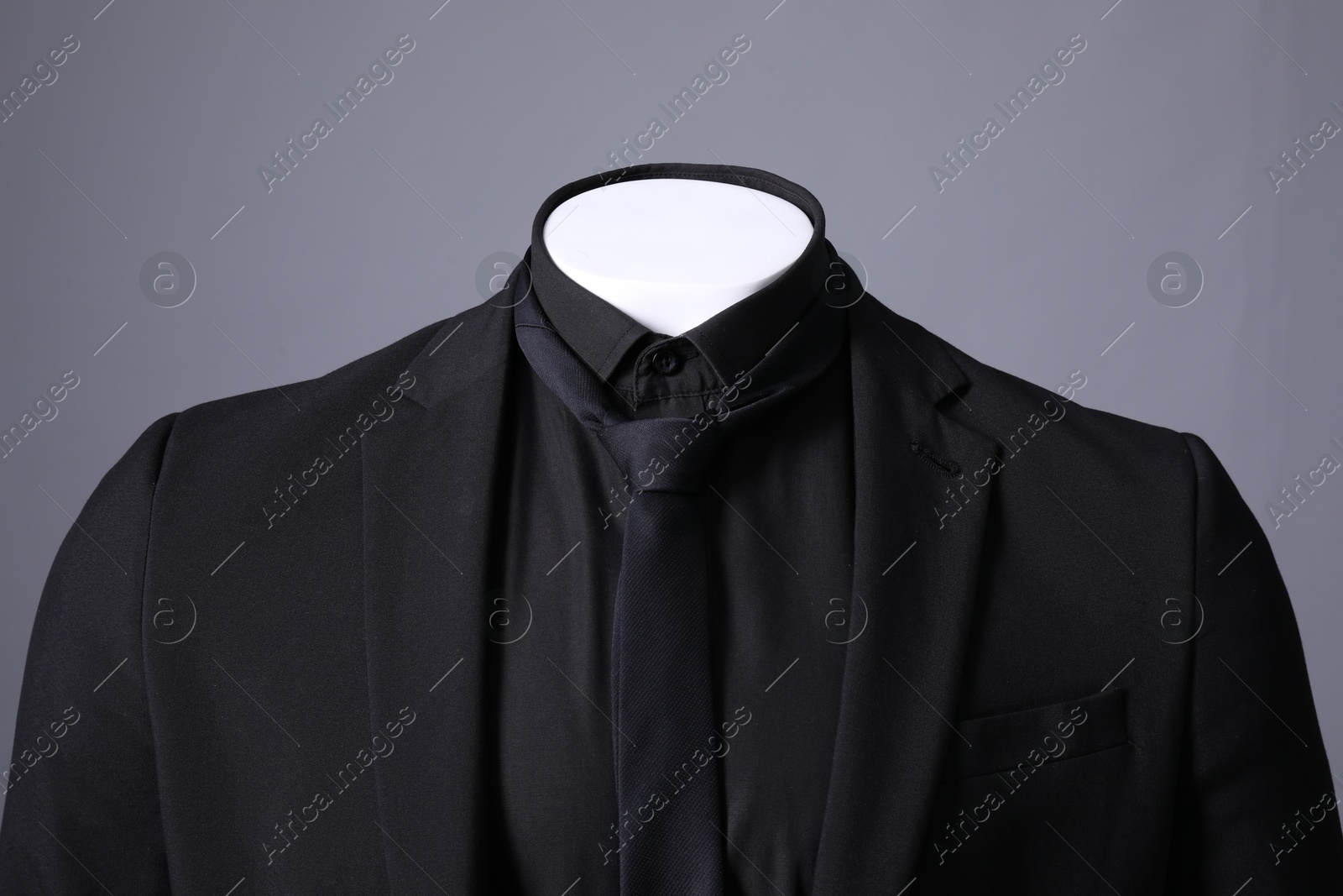 Photo of Male mannequin dressed in stylish black suit on grey background, closeup