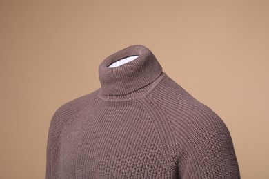 Male mannequin dressed in stylish sweater on beige background