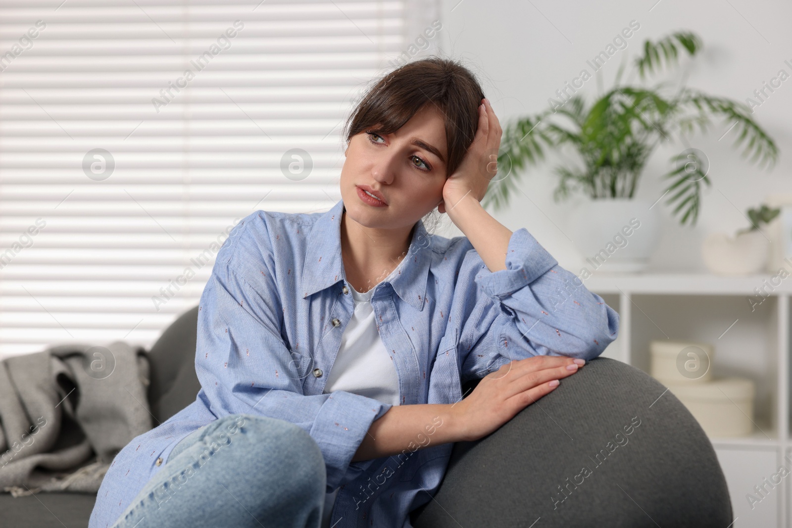 Photo of Loneliness concept. Sad woman sitting on sofa at home