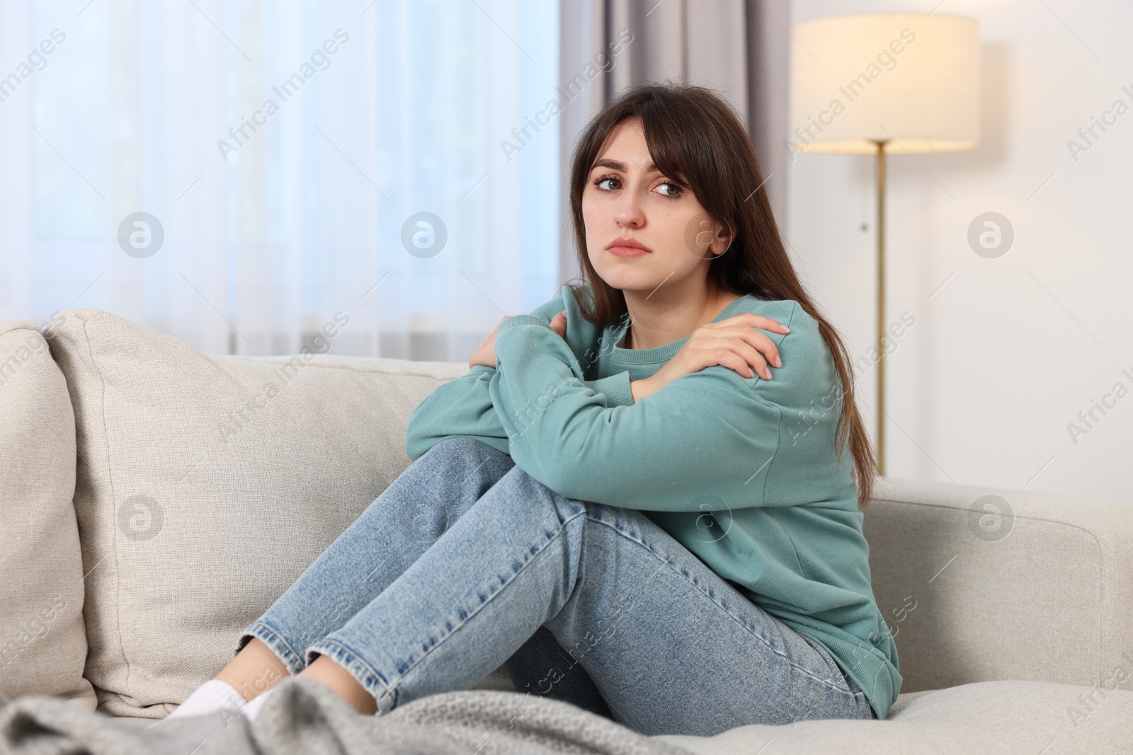 Photo of Loneliness concept. Sad woman sitting on sofa at home