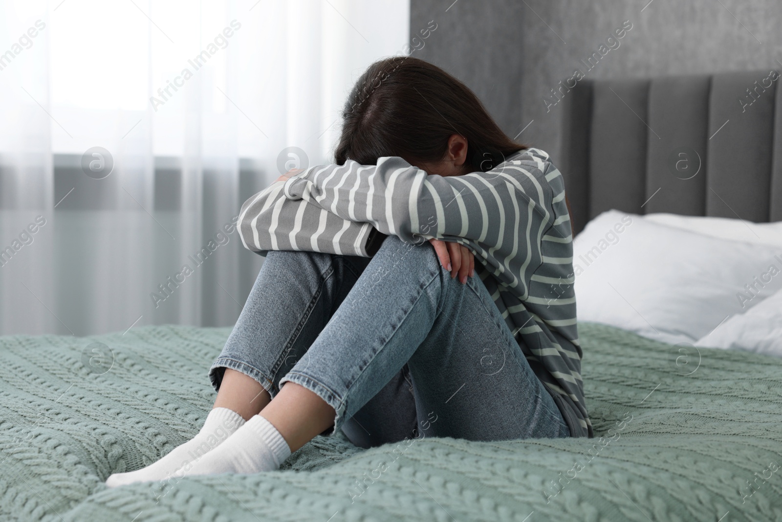 Photo of Loneliness concept. Sad woman sitting on bed at home