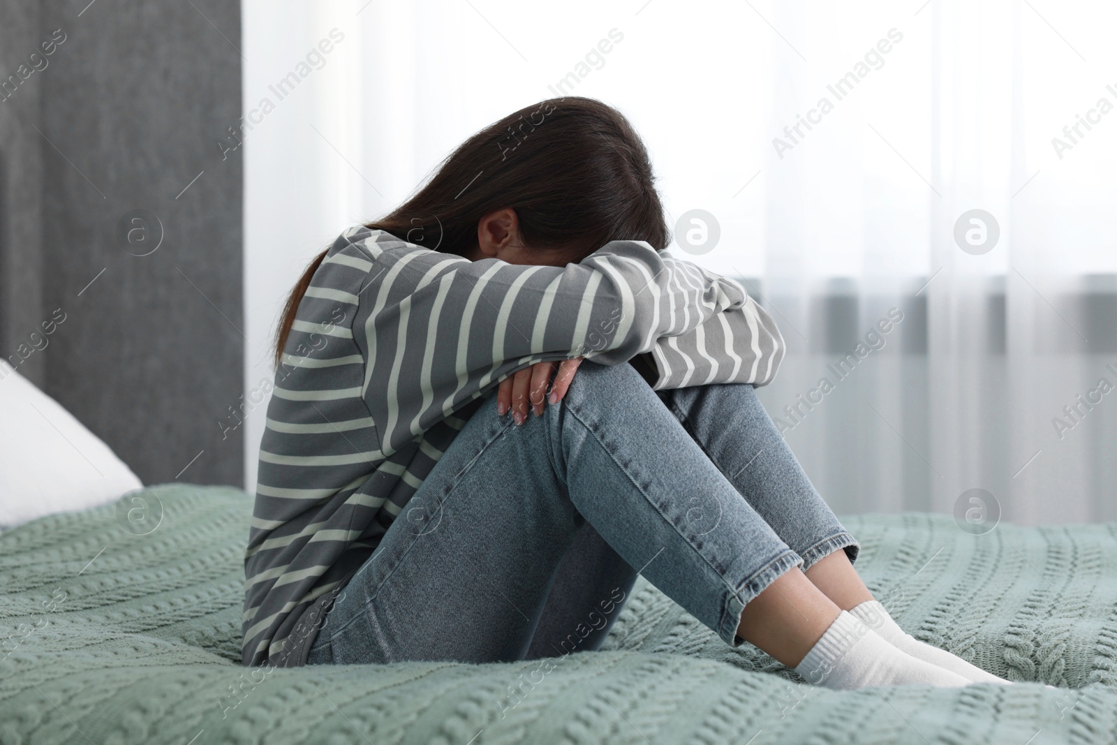 Photo of Loneliness concept. Sad woman sitting on bed at home