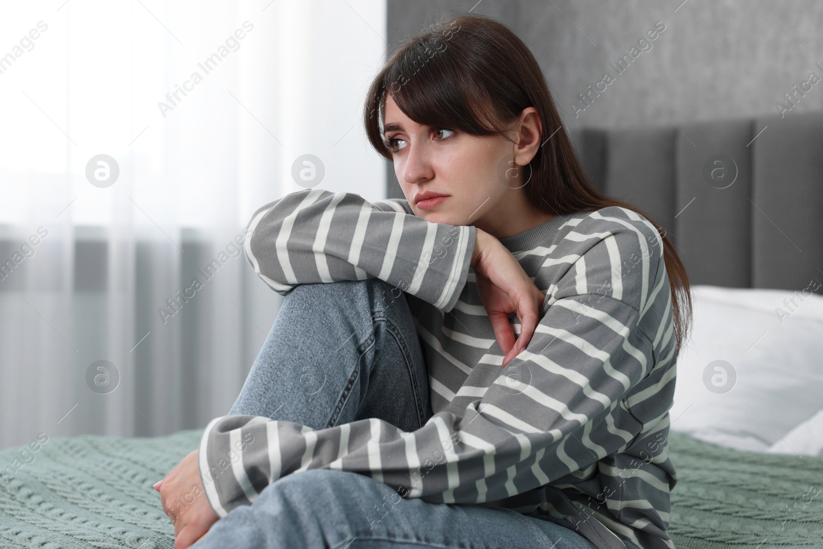 Photo of Loneliness concept. Sad woman sitting on bed at home