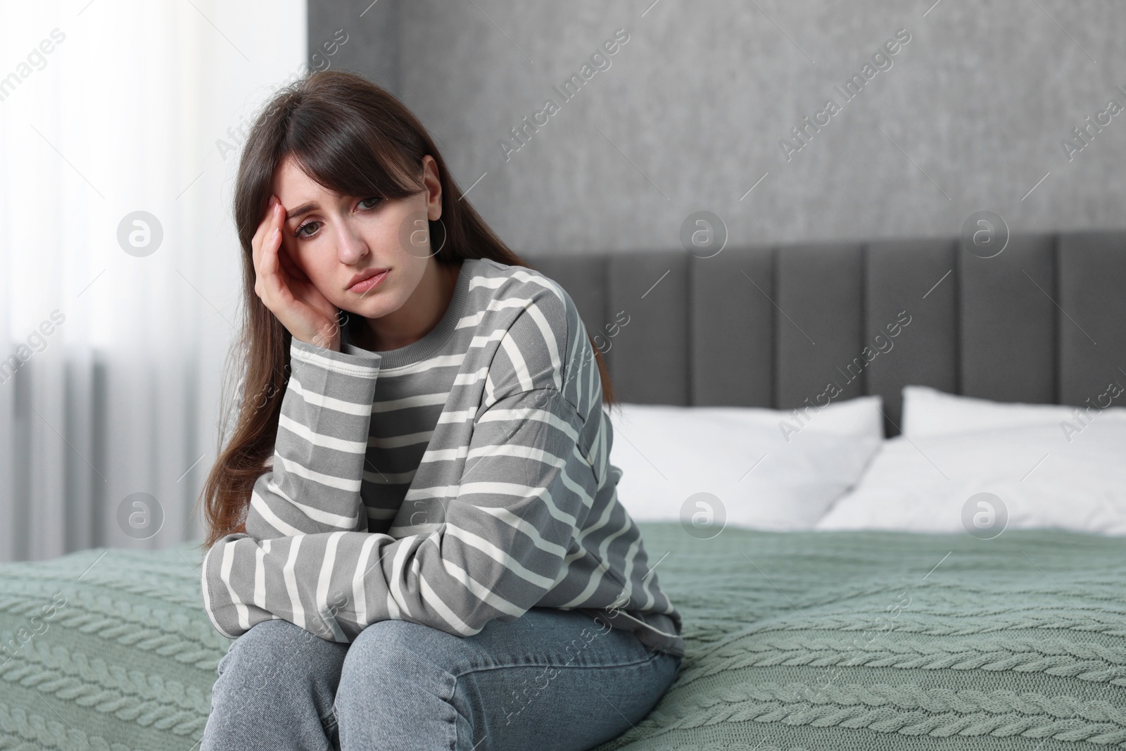 Photo of Loneliness concept. Sad woman sitting on bed at home, space for text