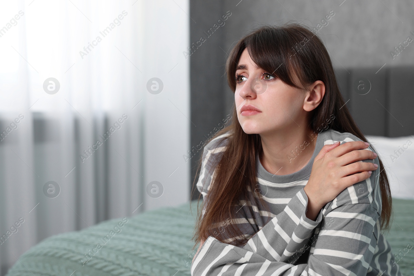 Photo of Loneliness concept. Sad woman sitting on bed at home, space for text