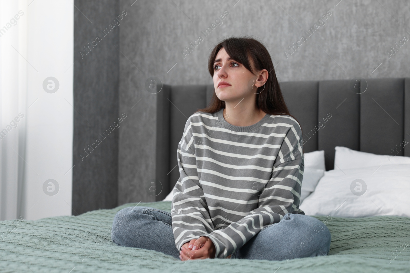 Photo of Loneliness concept. Sad woman sitting on bed at home