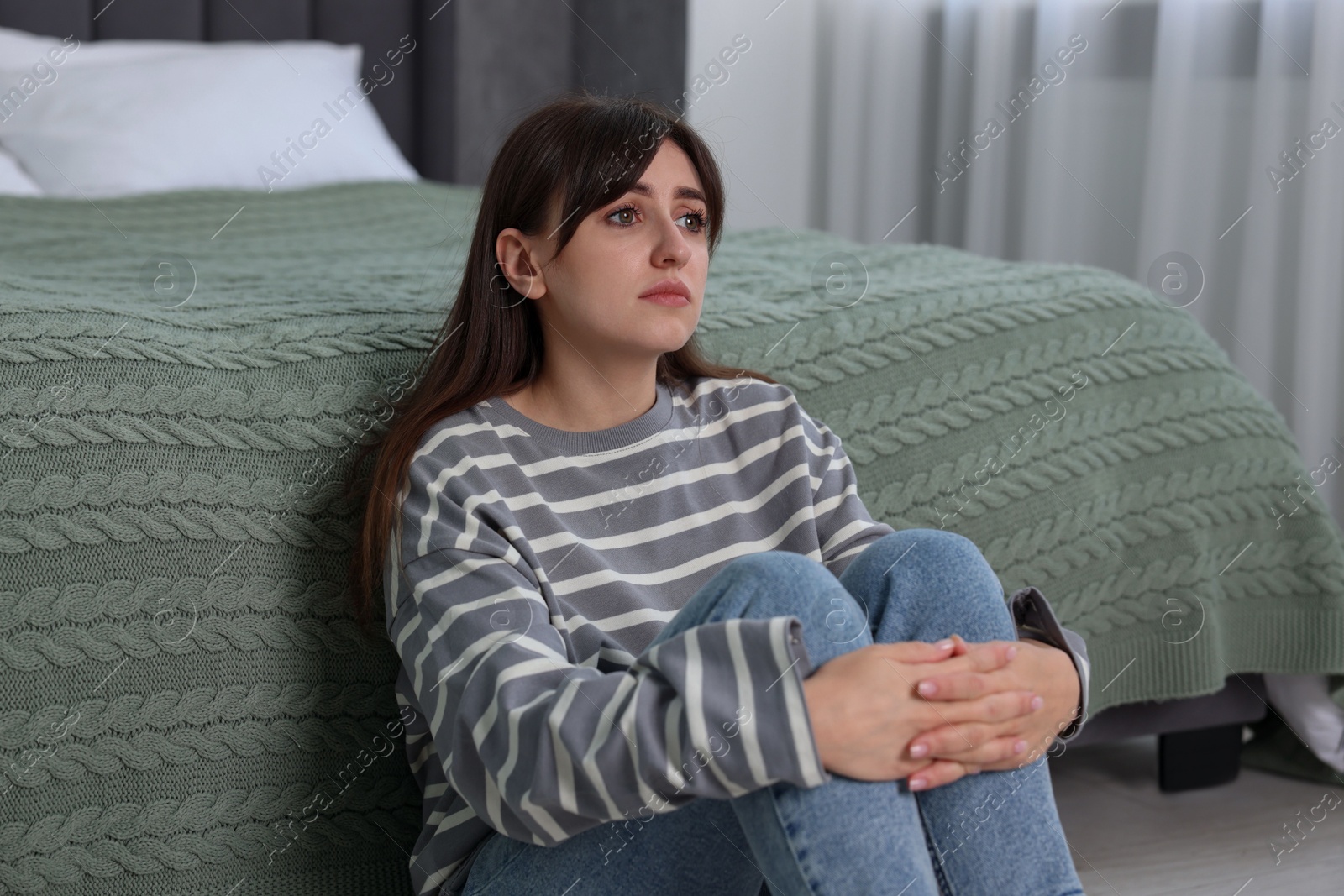 Photo of Loneliness concept. Sad woman sitting on floor at home