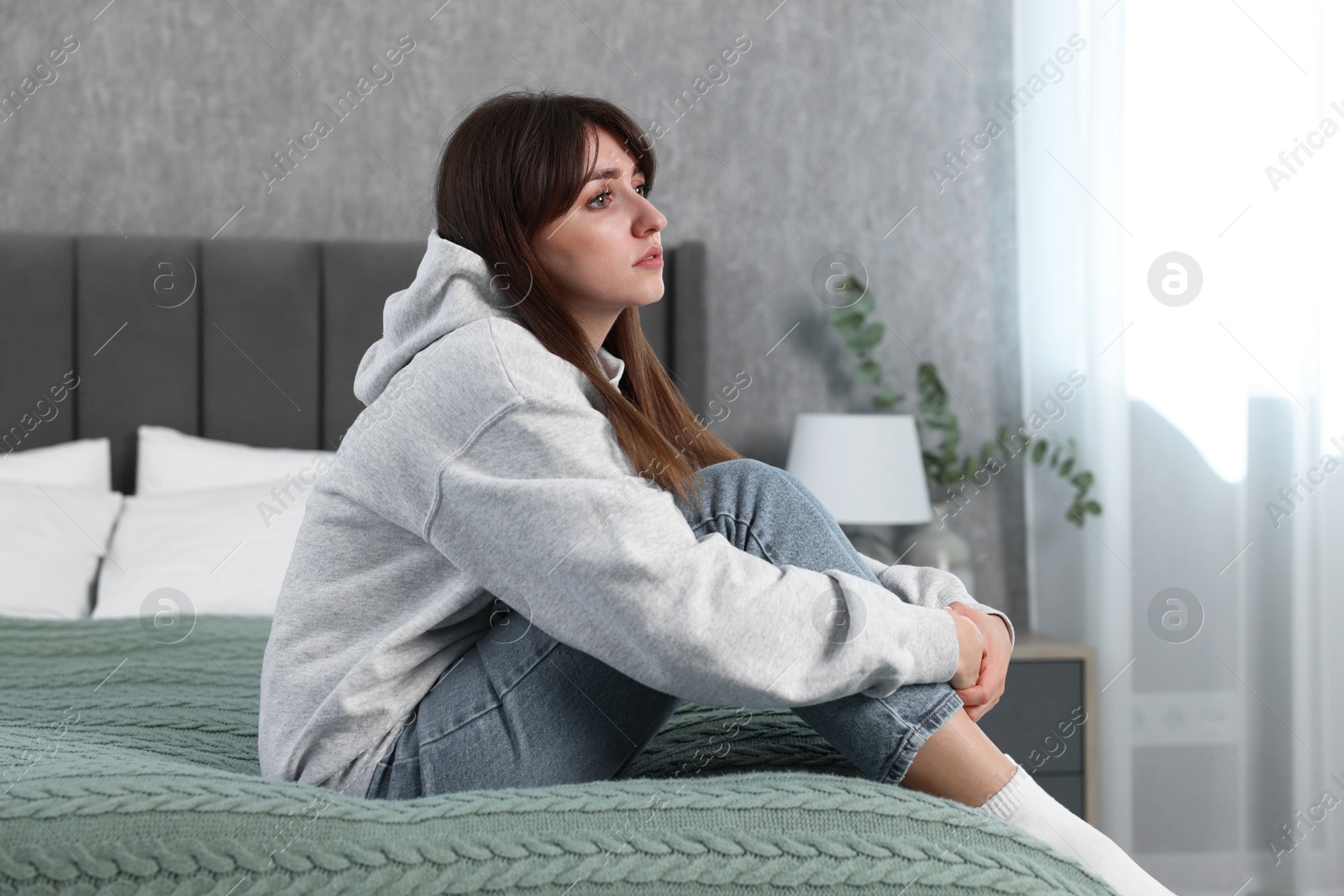 Photo of Loneliness concept. Sad woman sitting on bed at home