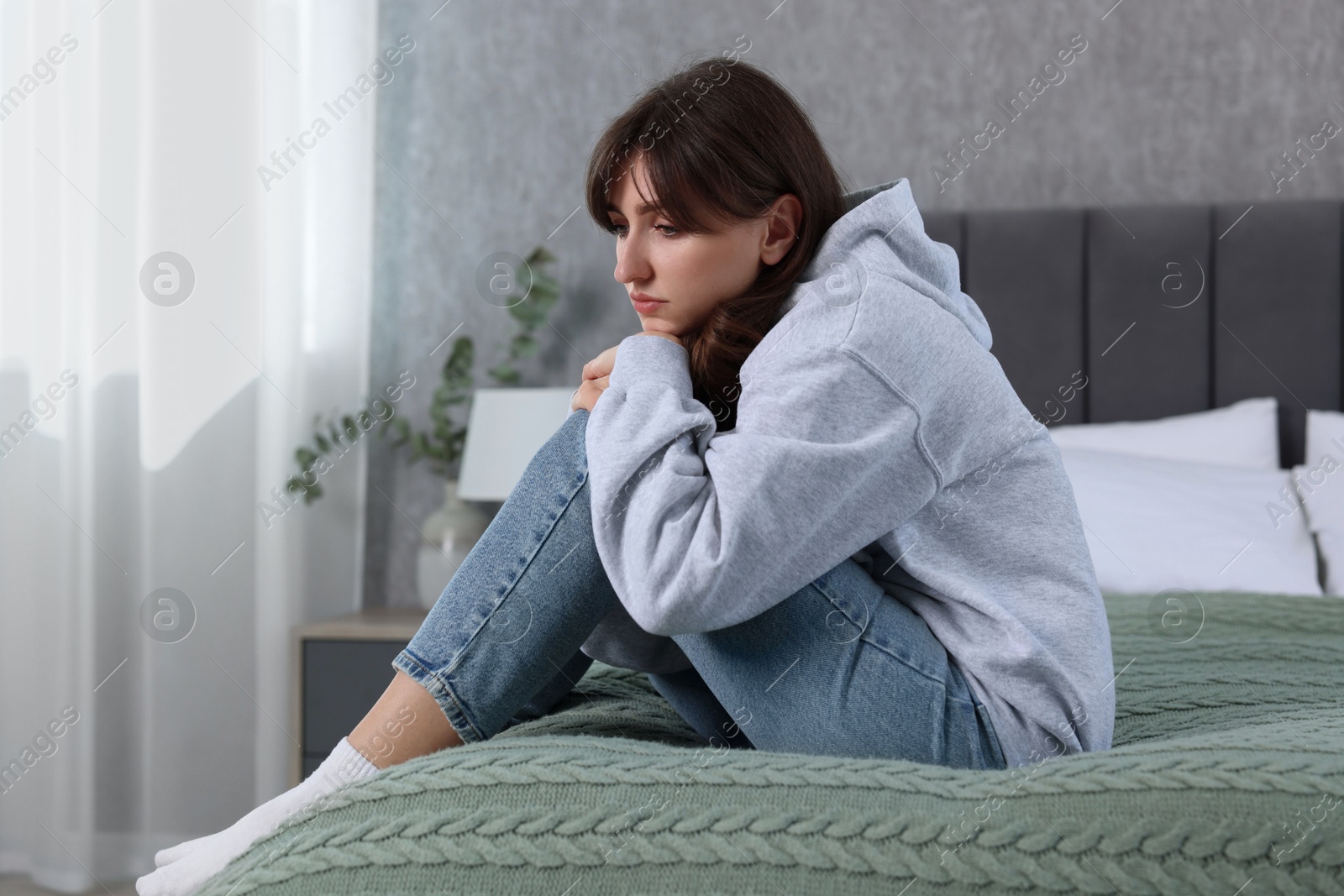 Photo of Loneliness concept. Sad woman sitting on bed at home