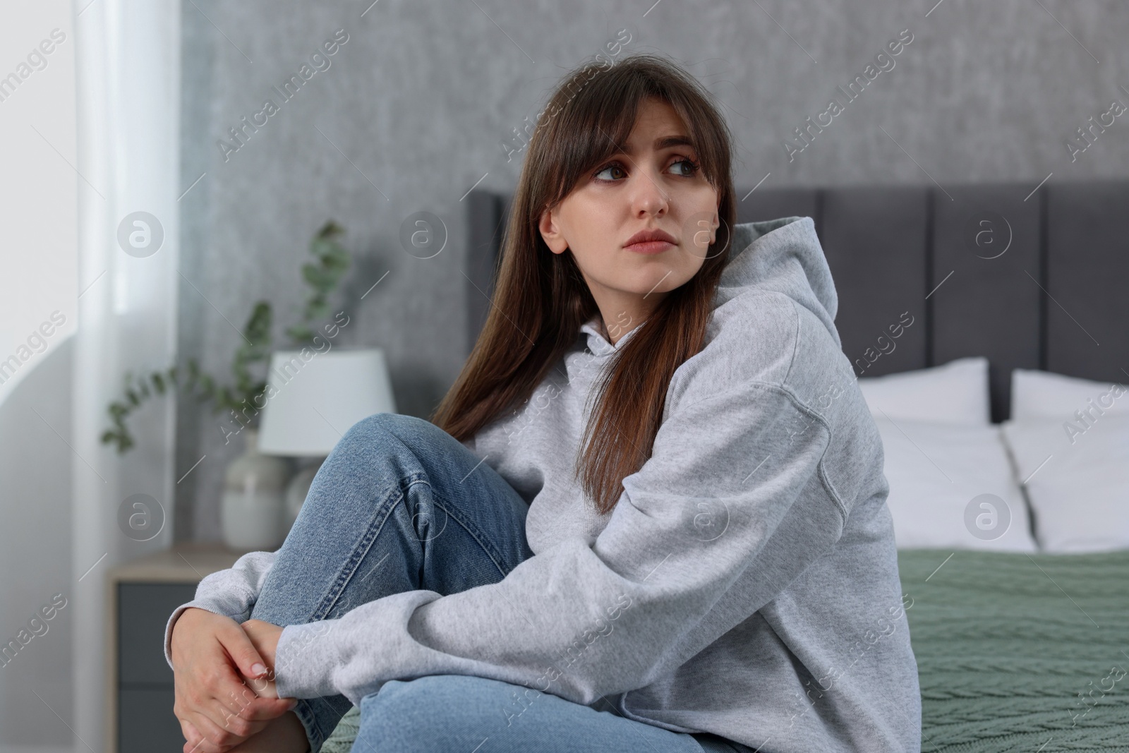 Photo of Loneliness concept. Sad woman sitting on bed at home