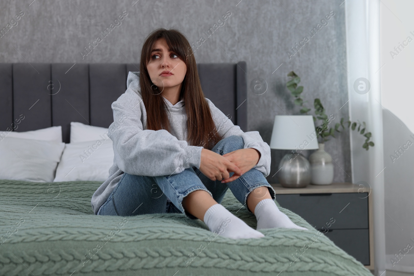 Photo of Loneliness concept. Sad woman sitting on bed at home