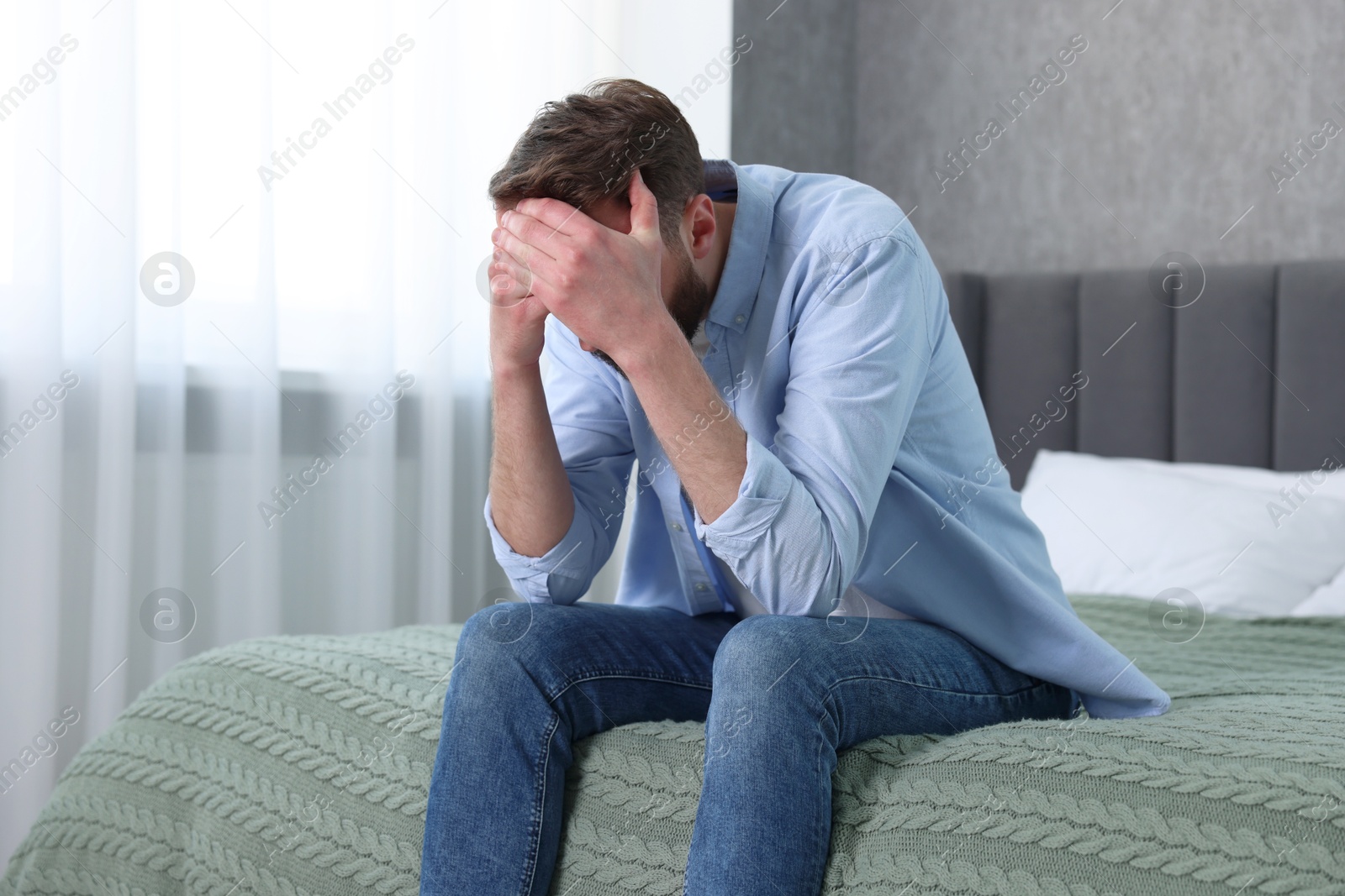 Photo of Loneliness concept. Sad man sitting on bed at home