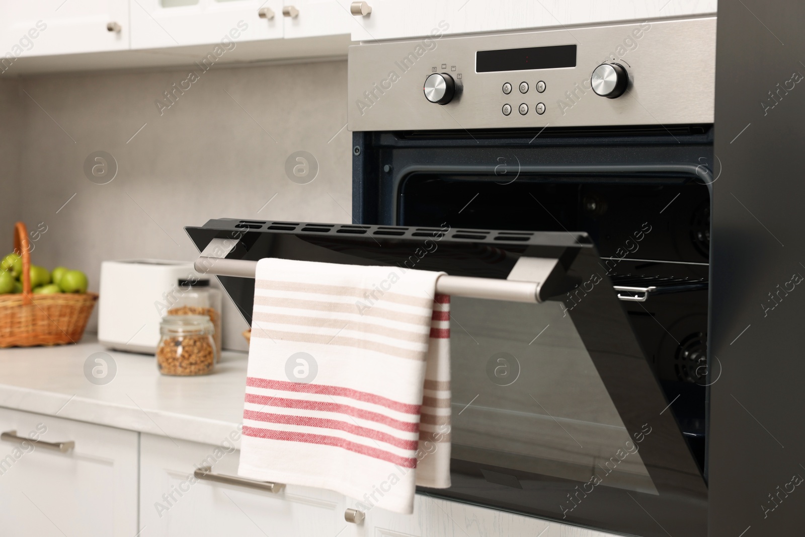 Photo of Open electric oven with towel in kitchen. Cooking appliance