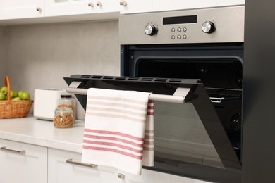 Open electric oven with towel in kitchen. Cooking appliance