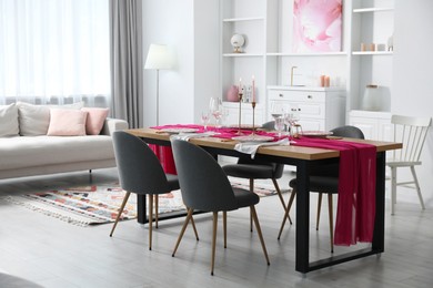 Beautiful table setting with pink accent and chairs in dining room