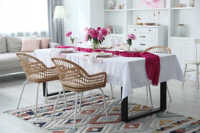 Photo of Beautiful table setting with pink accent and rattan chairs in dining room