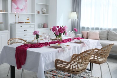 Photo of Beautiful table setting with pink accent and rattan chairs in dining room