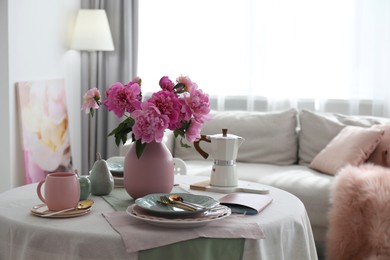 Photo of Beautiful table setting with pink peonies in living room