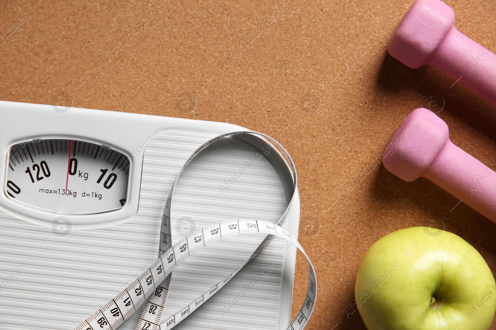 Photo of Scale, measuring tape, dumbbells and fresh apple on brown textured background, flat lay