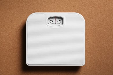 Photo of One bathroom scale on brown textured background, top view