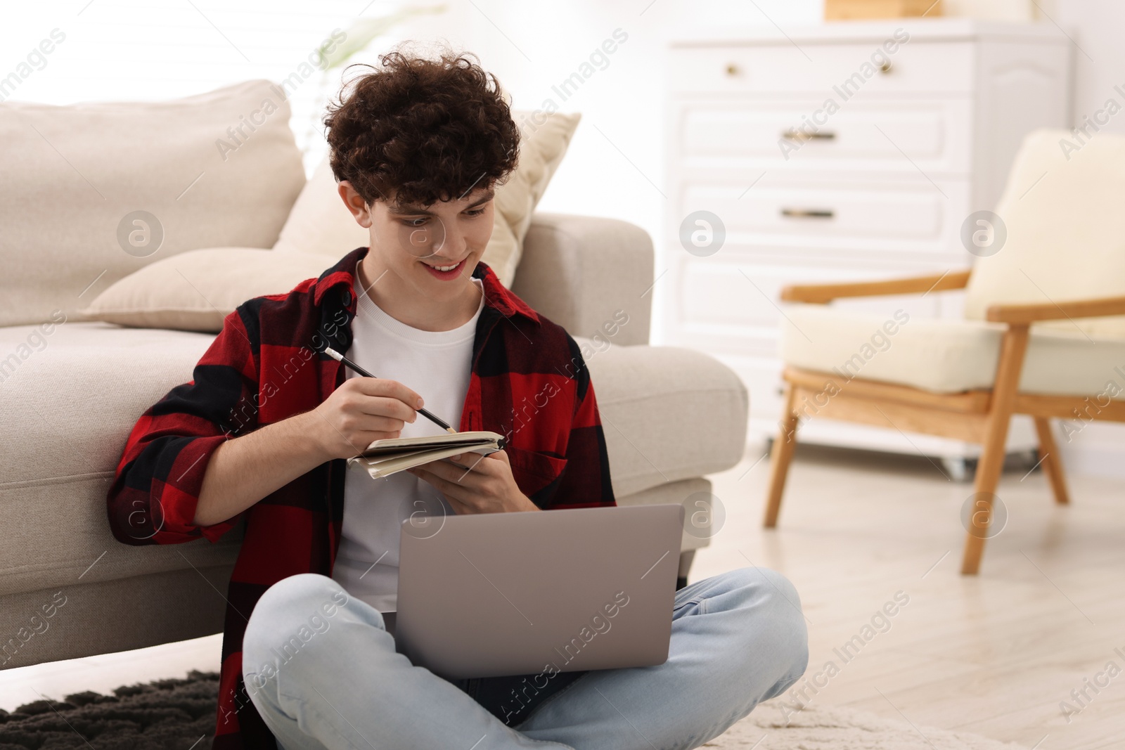 Photo of Teenager taking notes while working with laptop at home, space for text. Remote job