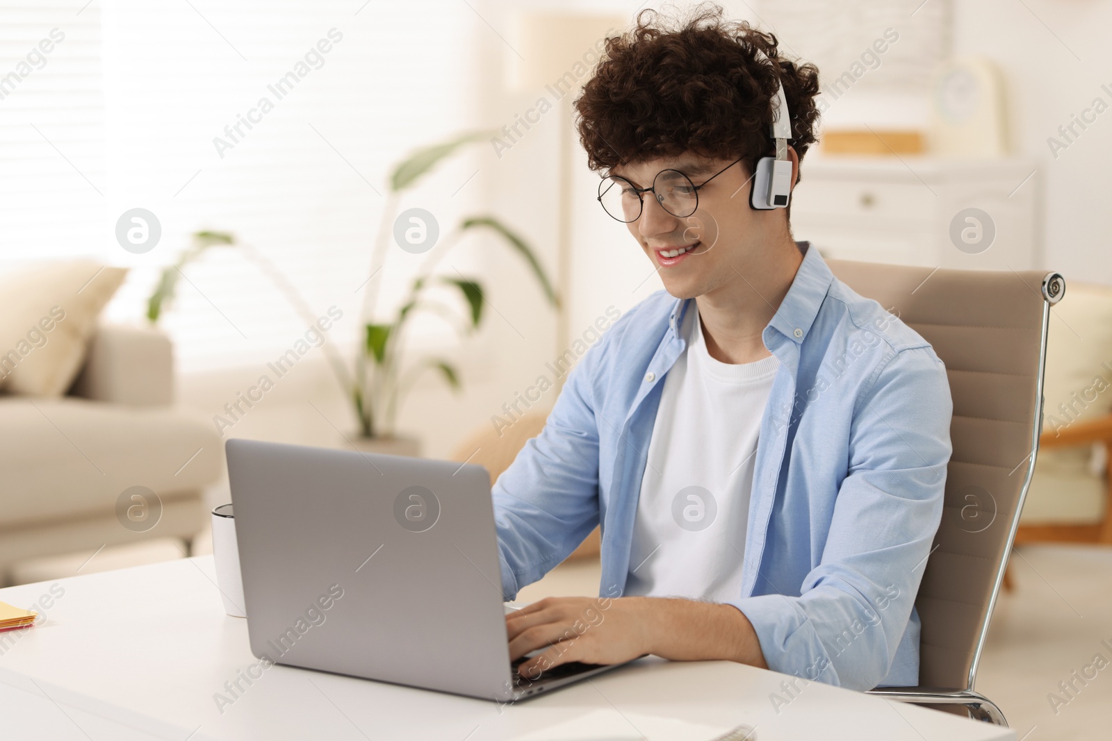 Photo of Teenager in headphones working with laptop at home. Remote job