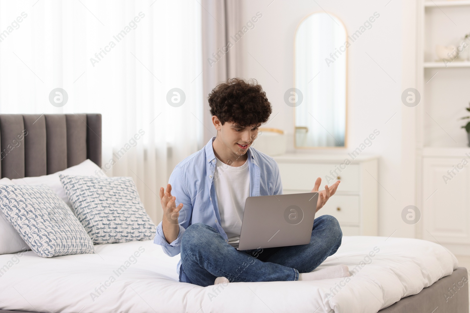 Photo of Teenager having video chat via laptop on bed at home. Remote work