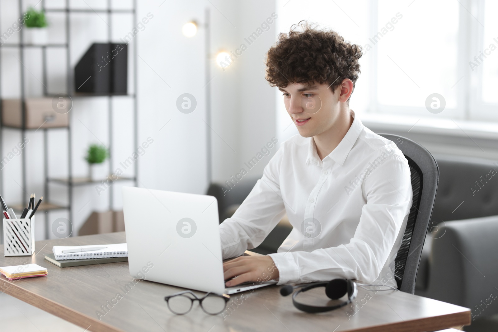 Photo of Teenager working with laptop at table indoors. Remote job