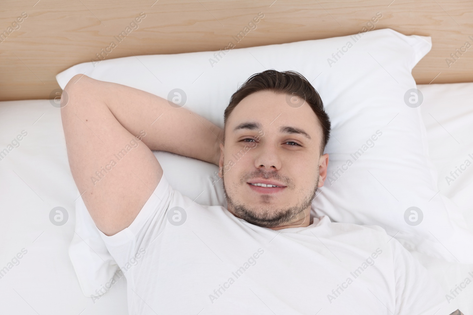 Photo of Bedtime. Handsome man lying in bed indoors, above view