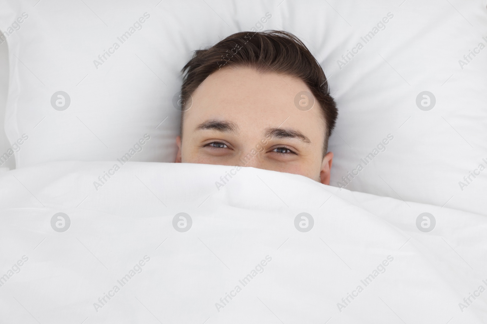 Photo of Bedtime. Handsome man lying in bed indoors, top view