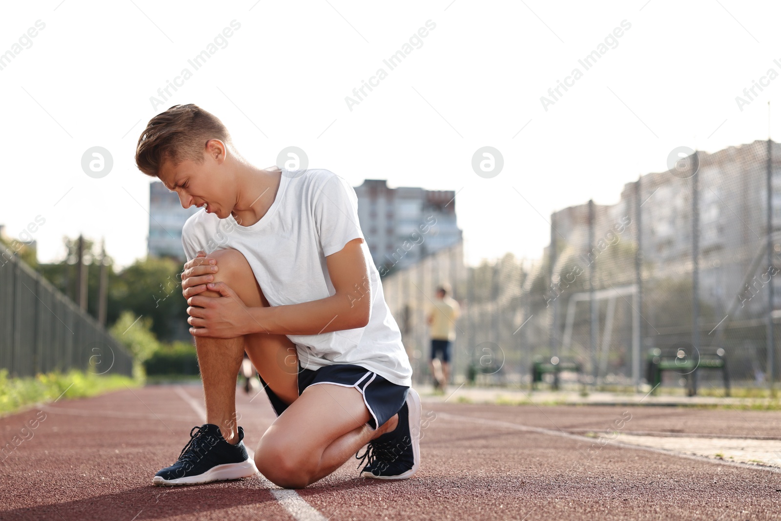 Photo of Sportsman with leg injury suffering from knee pain at stadium, space for text