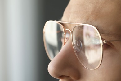 Photo of Vision correction. Man in glasses on blurred background, closeup. Space for text