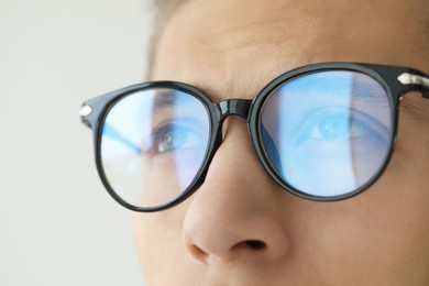 Photo of Vision correction. Man wearing glasses on blurred background, closeup