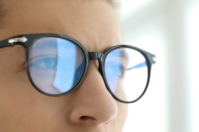 Photo of Vision correction. Man wearing glasses on blurred background, closeup
