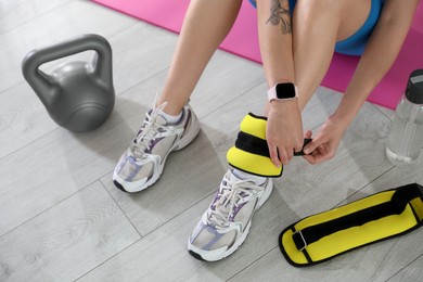 Photo of Woman putting on ankle weights indoors, above view