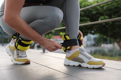 Woman putting on ankle weights outdoors, closeup