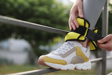 Photo of Woman putting on ankle weights outdoors, closeup. Space for text