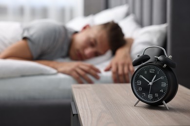 Photo of Man sleeping in bed at lunch time, focus on alarm clock