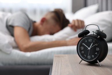 Photo of Man sleeping in bed at lunch time, focus on alarm clock