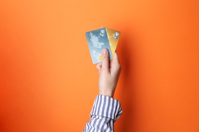 Photo of Woman holding credit cards on orange background, closeup