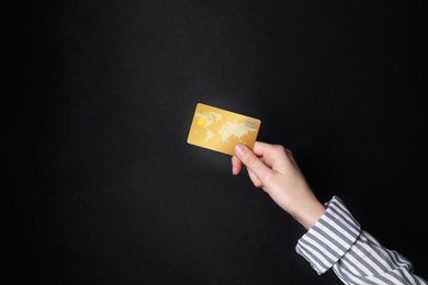 Woman holding credit card on black background, closeup