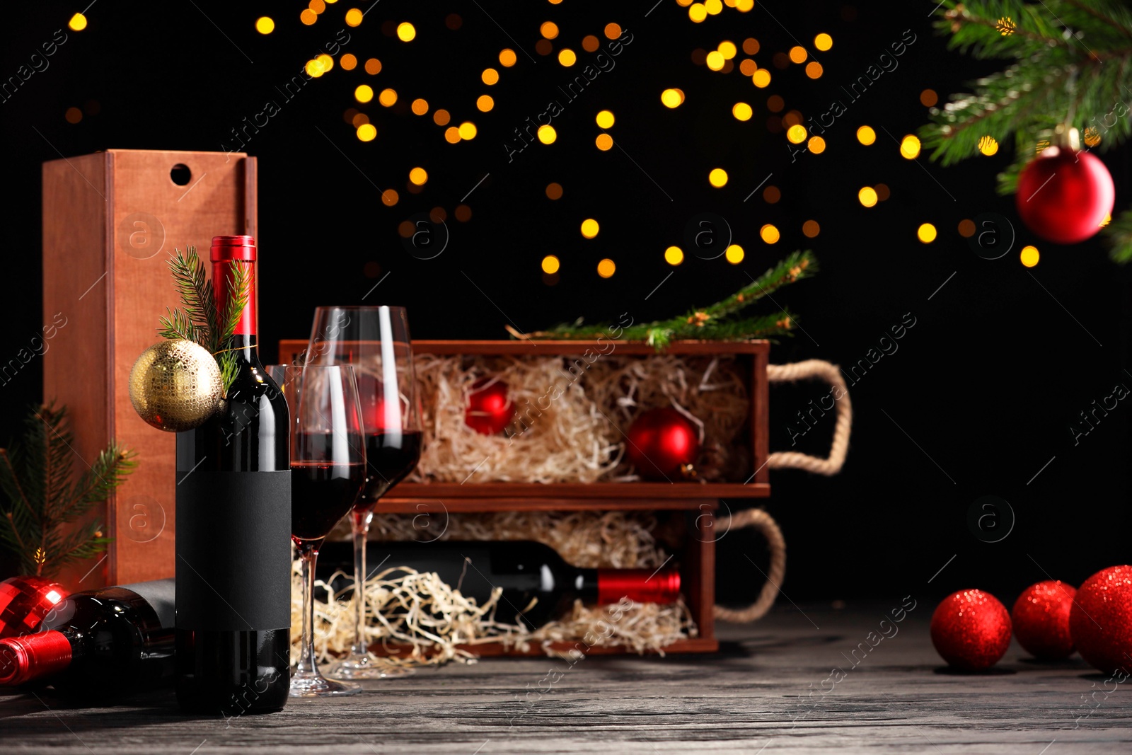 Photo of Bottles of wine, glasses, wooden boxes, fir twigs and Christmas balls on table