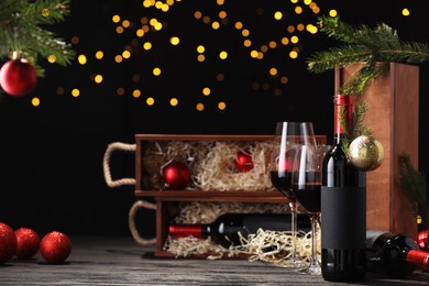 Photo of Bottles of wine, glasses, wooden boxes, fir twigs and Christmas balls on table