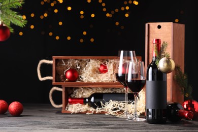Photo of Bottles of wine, glasses, wooden boxes, fir twigs and Christmas balls on table