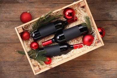 Photo of Wooden crate with bottles of wine, fir twigs and red Christmas balls on table, top view